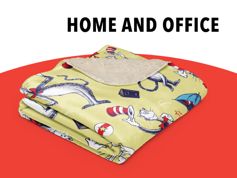 Dr. Seuss Official Store Home Goods banner. Features a folded yellow sherpa blanket with a Cat in the Hat character pattern on a red and white background with white text "HOME GOODS." - Banner